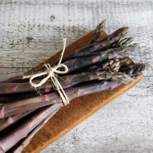 Purple Precoce D'Argentuil Asparagus freshly harvested and tied with twine on a wooden chopping board