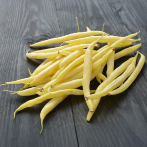 A cluster of freshly harvested yellow bergold beans on a grey wooden surface