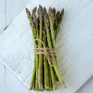 Green UC 157 F2 Asparagus freshly harvested and tied with twine on a white wooden surface