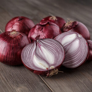 Red Baron Onions on a wooden surface with one sliced in half