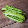Frilled, fresh green aparagus that looks similar to peas, on a wooden table