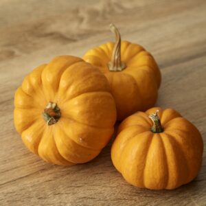 Mini Jack Be Little orange yellow pumpkins freshly harvested on a wooden surface