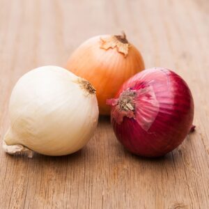 A mix of onions on a wooden surface