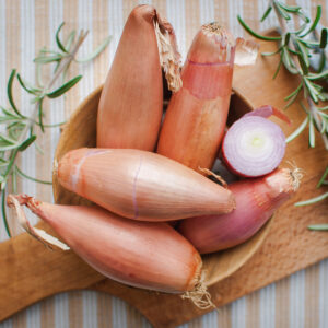 Longor shallots in a bowl on a wooden surface with rosemary