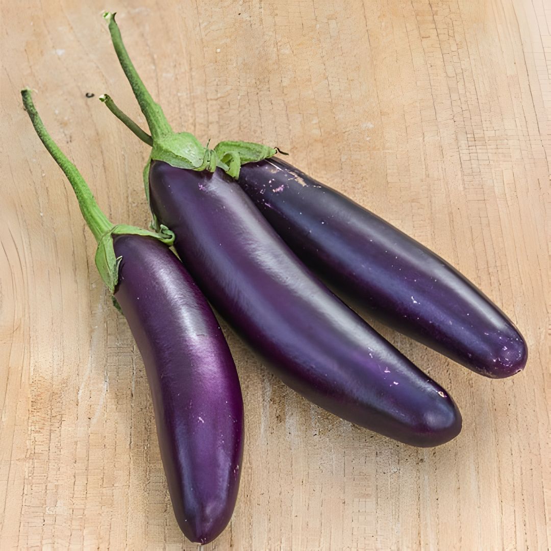 Three harvested Purple Knight Aubergines on a wooden surface.