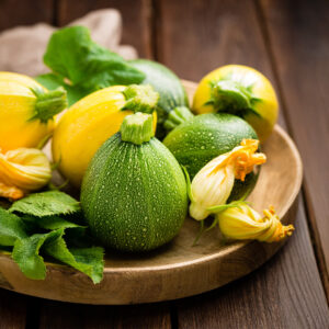 Ball Mix of courgettes in green and yellow, freshly harvested in a wooden bowl