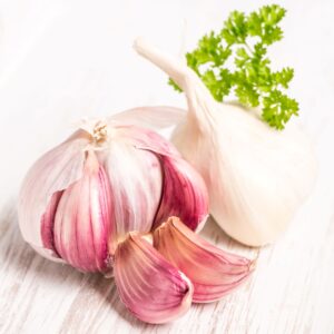 A Morado Garlic bulb on a white wooden surface with separated cloves
