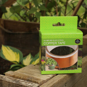 A green cardboard box of Slug and Snail Copper Tape is sat on a wooden planter with a blurred hosta in the background