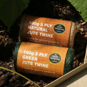Two packets of twine in natural jute and green jute laying on the floor of a greenhouse