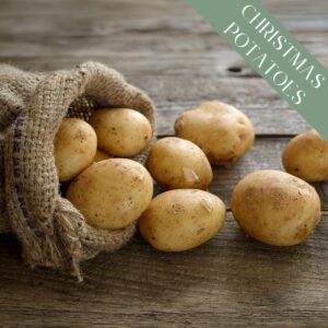 Freshly harvested Maris Peer potatoes tumbling out of hessian onto a wooden surface